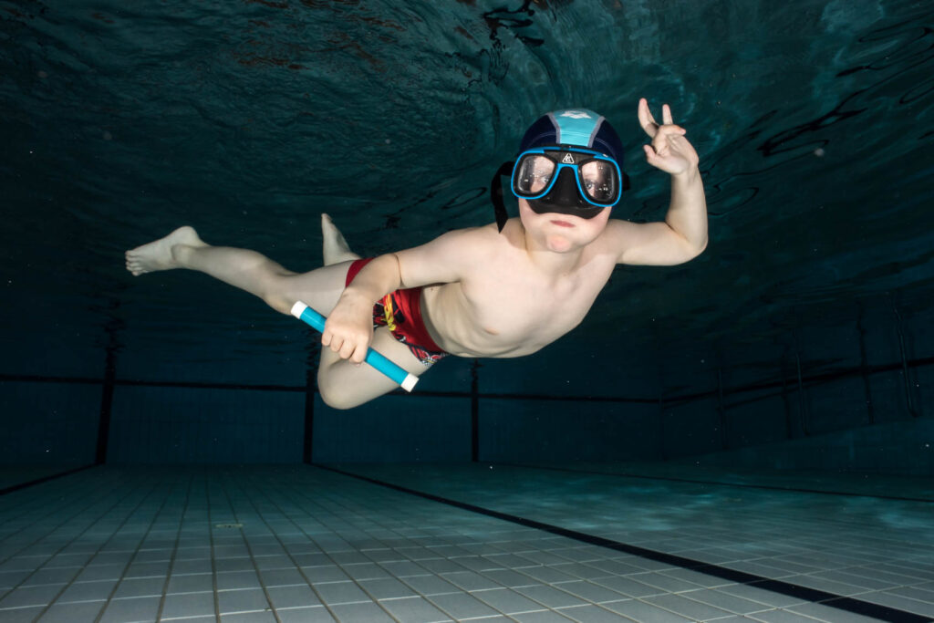 Barnesvømmer som dykker etter pinne