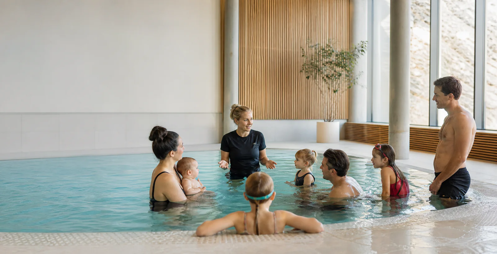 Instruktør med deltakere på svømmekurs for babyer, barn og voksne